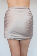 Beige satin skirt worn by a person on a plain background